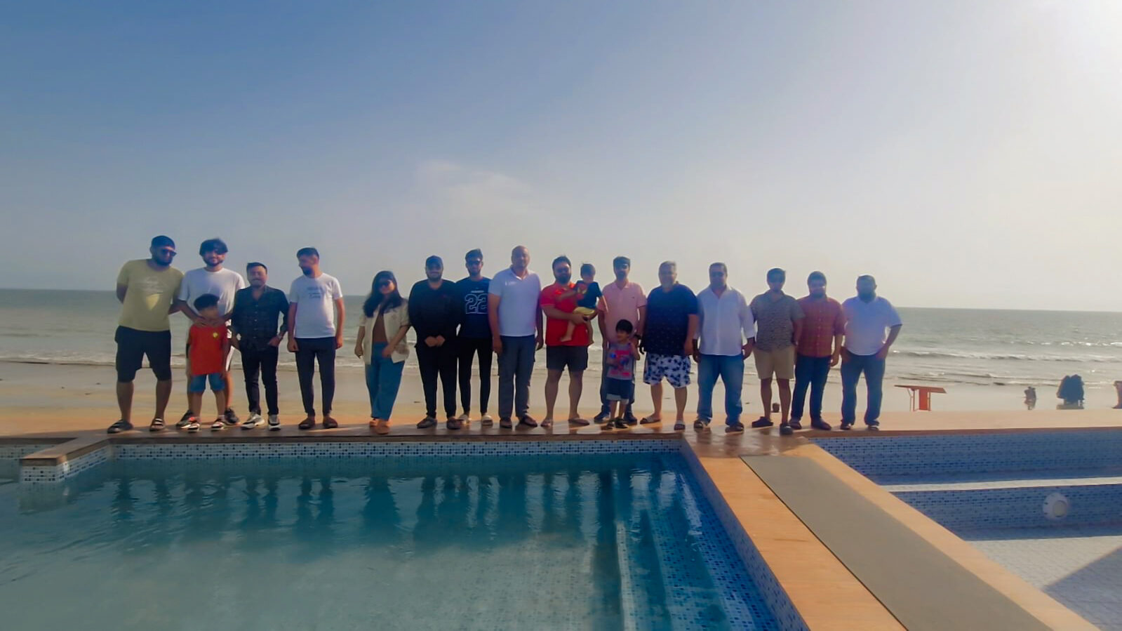 Deliverydevs picnic 2025: the whole team lined up by the pool with the sea behind